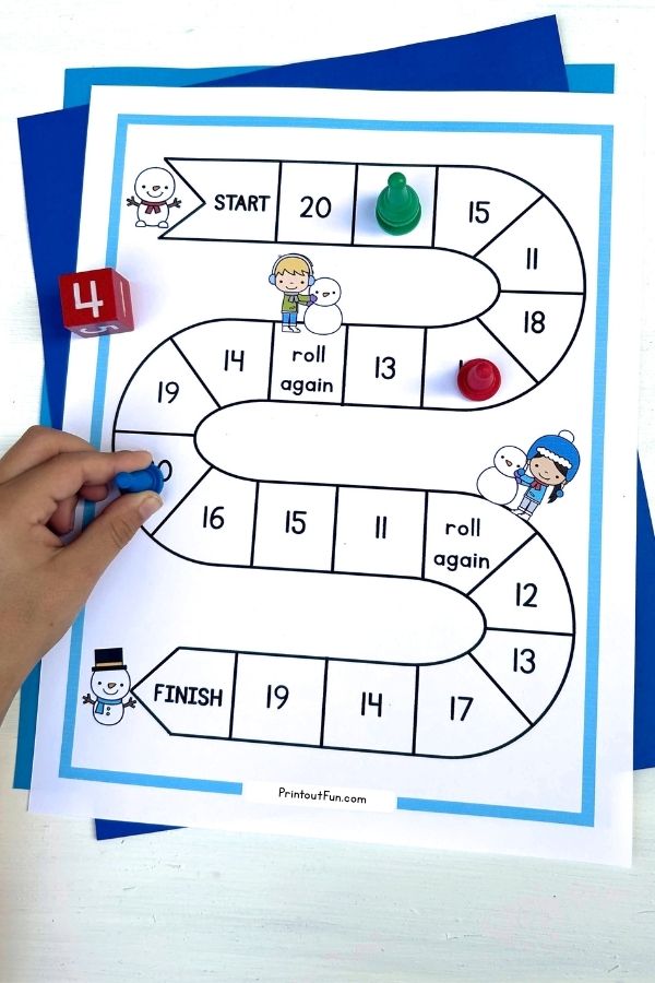 A child's hand moving a game pawn on the snowman number recognition board game.