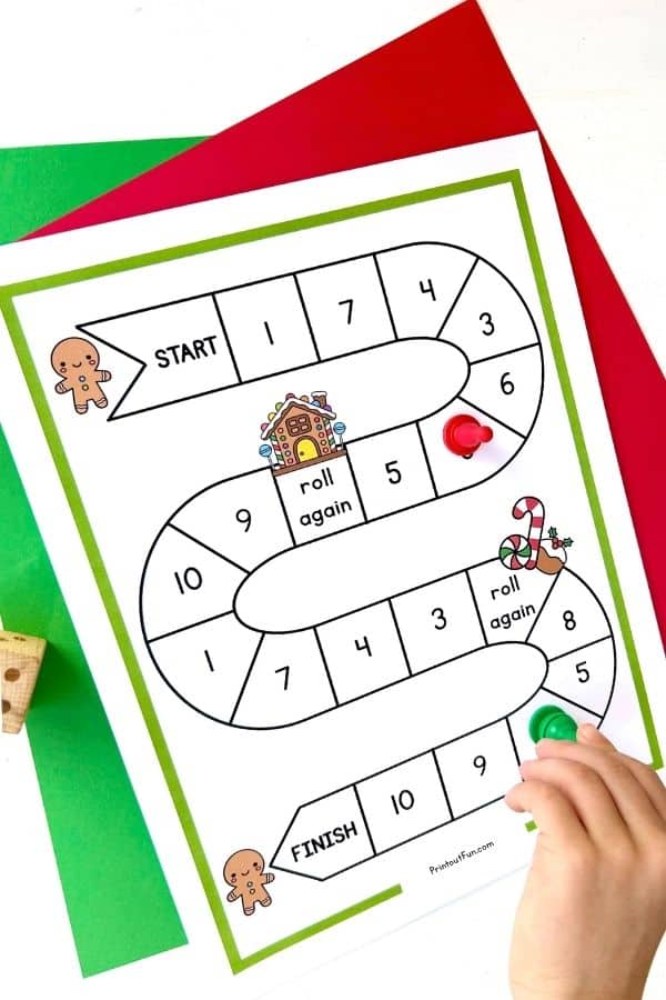 A child's hand moving a game pawn on the gingerbread number recognition game. 