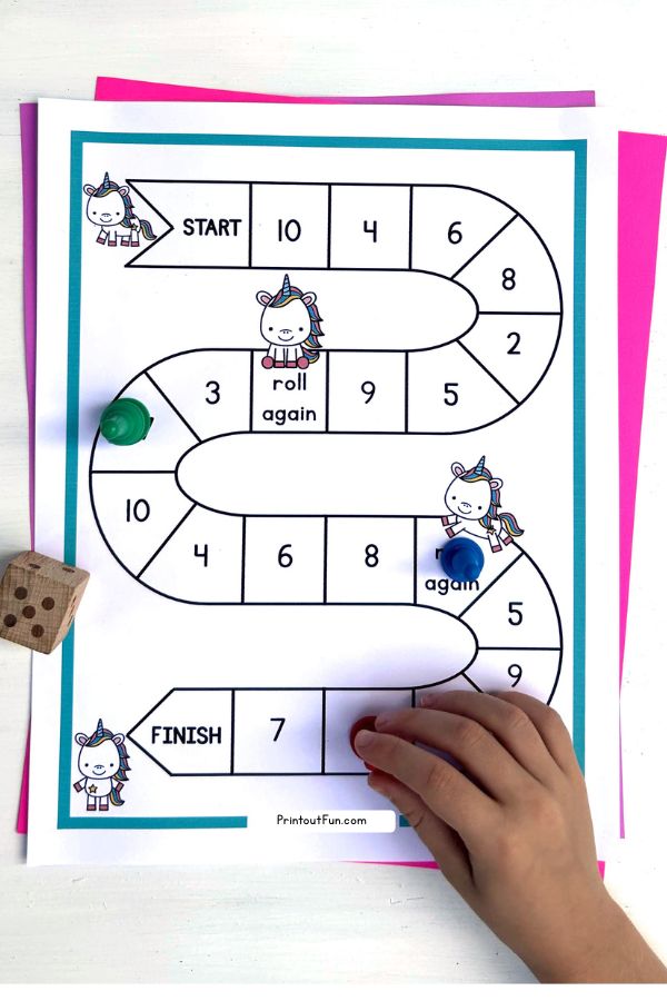 A child's hand moving a game piece on the unicorn number recognition game board.