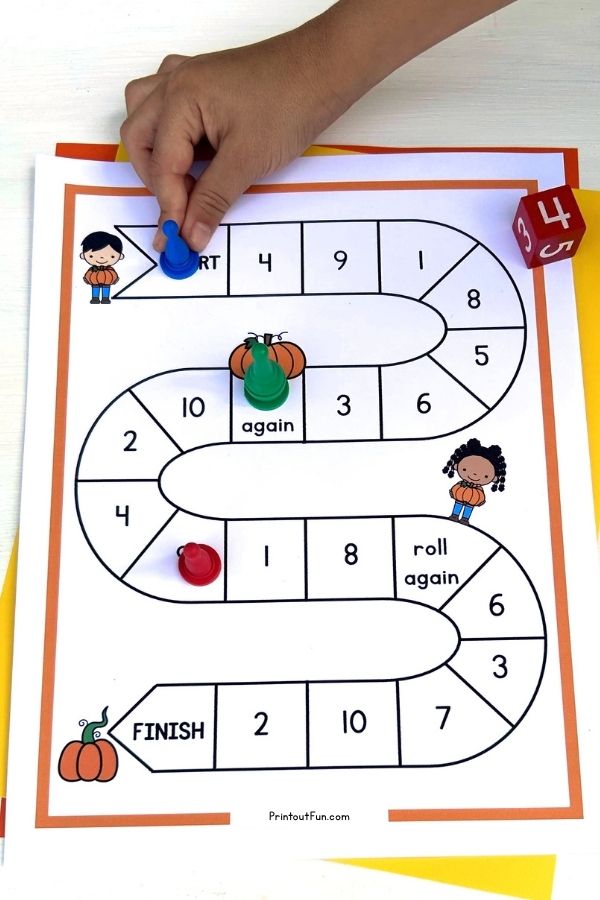 Child's hand moving a game pawn on the 1-10 pumpkin number recognition board game.